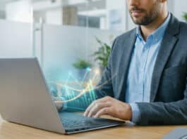 IG : Actions et ETF sans commission en 2026 Homme travaillant sur un ordinateur portable affichant des graphiques financiers lumineux et une flèche de croissance, dans un bureau moderne.