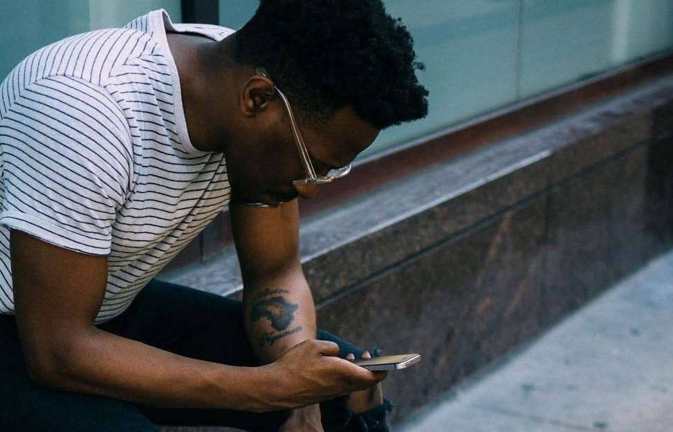 Photo d'un homme assis qui regarde son smartphone