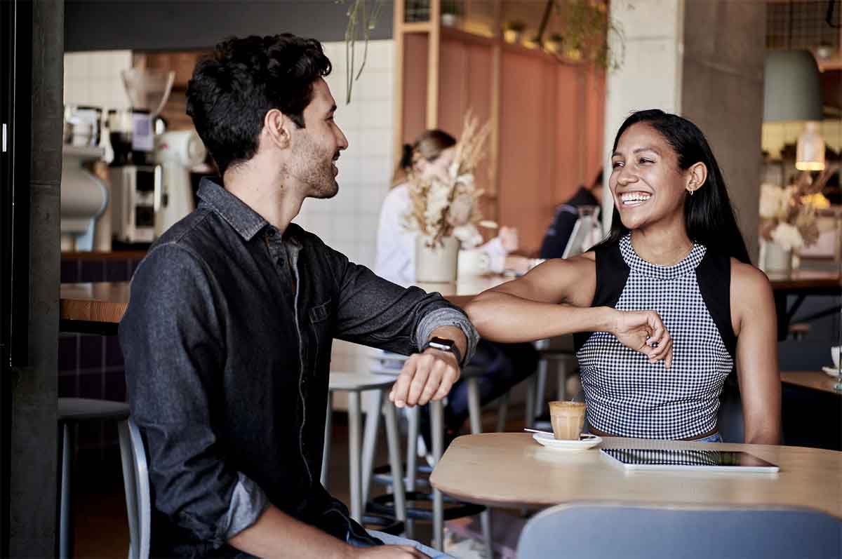 Photo de deux personnes souriantes faisant un check du coude