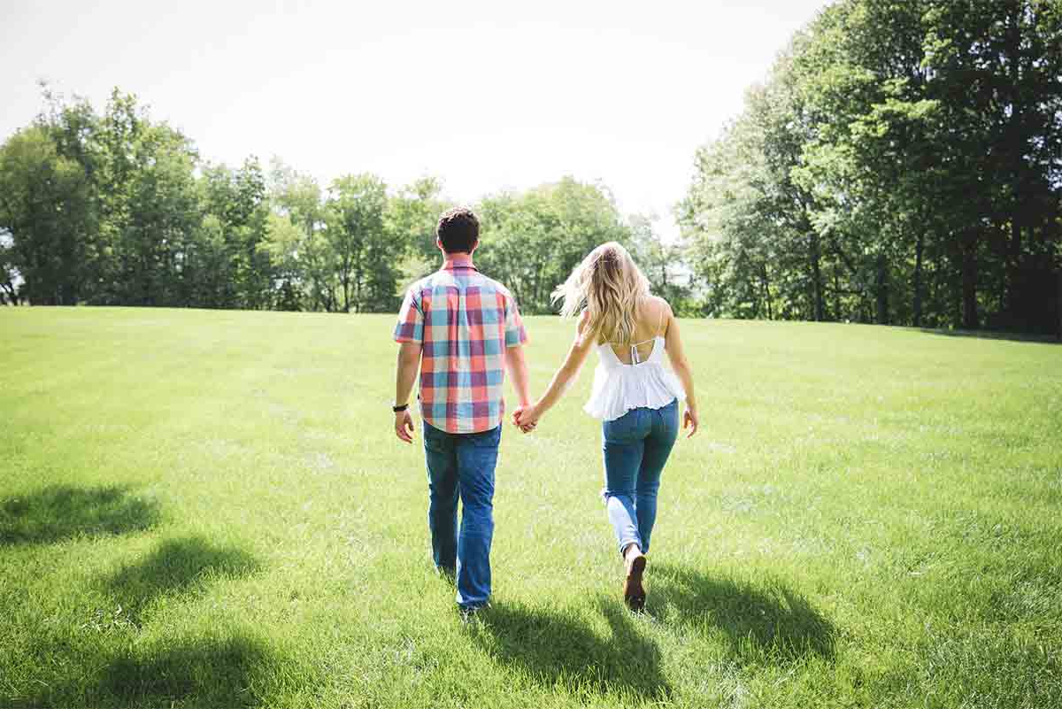 Photo d'un couple se tenant par la main et marchant sur l'herbe