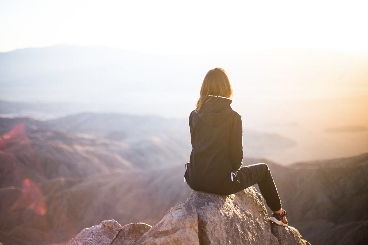 Photo d'une femme en haut d'une montagne regardant le paysage