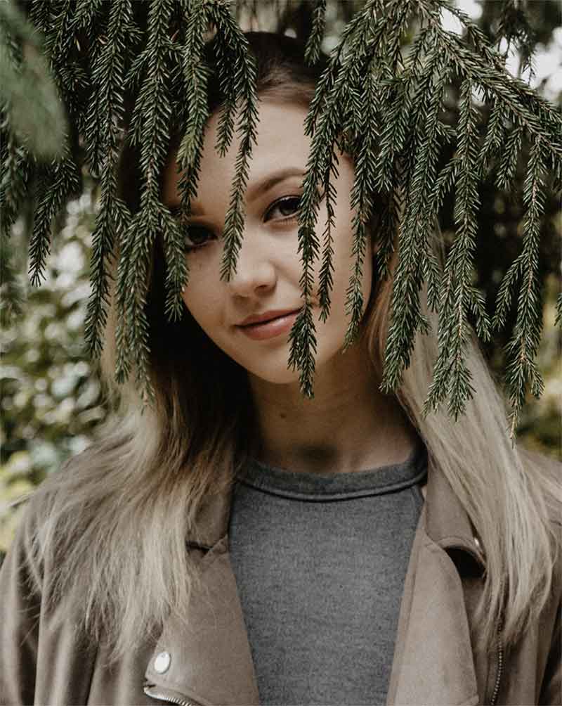 Photo d'une femme derriere une branche de pin