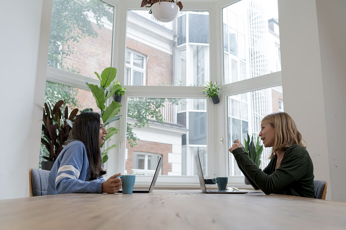Photo de 2 femmes parlant devant une fenetre