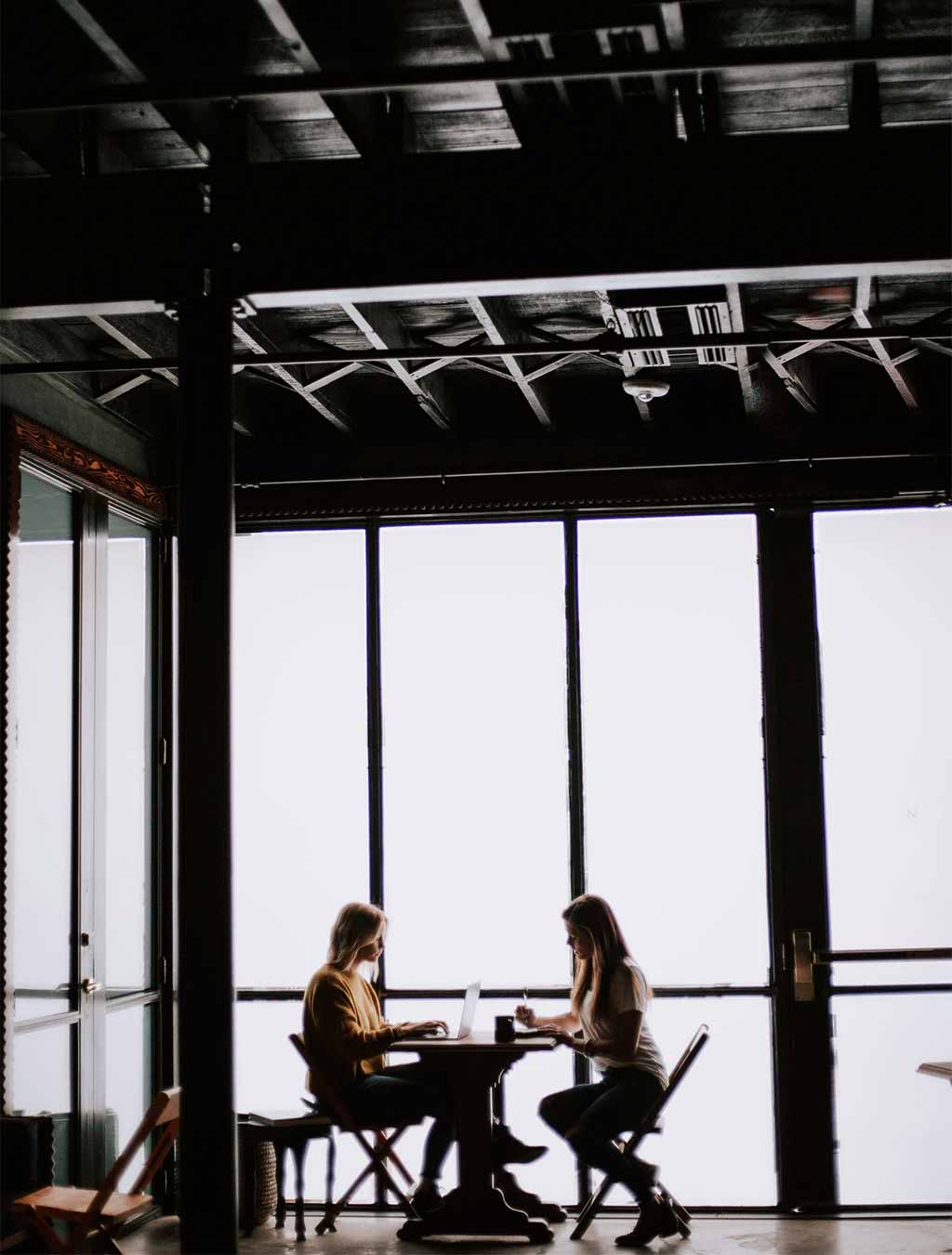 Photo deux femmes devant une fenêtre à une table