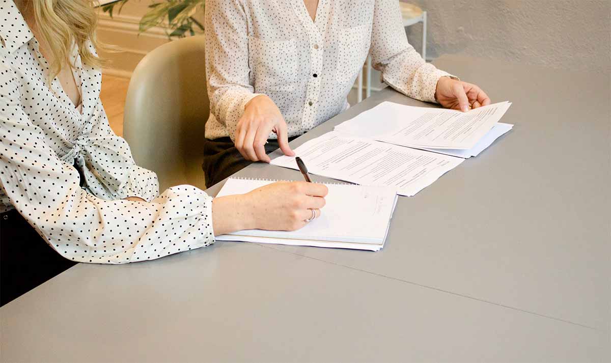 Photo de deux femmes prenant des notes sur un bureau