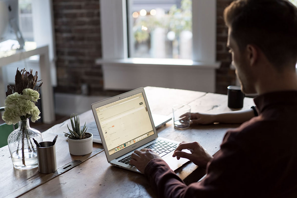 Photo d'un jeune homme devant un mackbook avec des fleurs