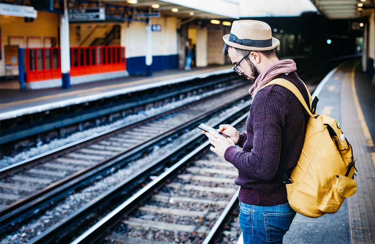 Photo homme attendant son train regardant son smartphone