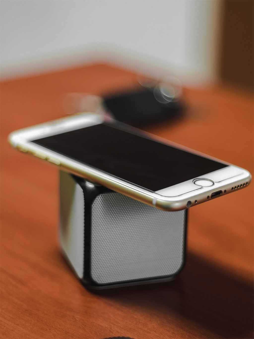 Photo d'un iphone posé sur un bloc cubique d'enceinte portative