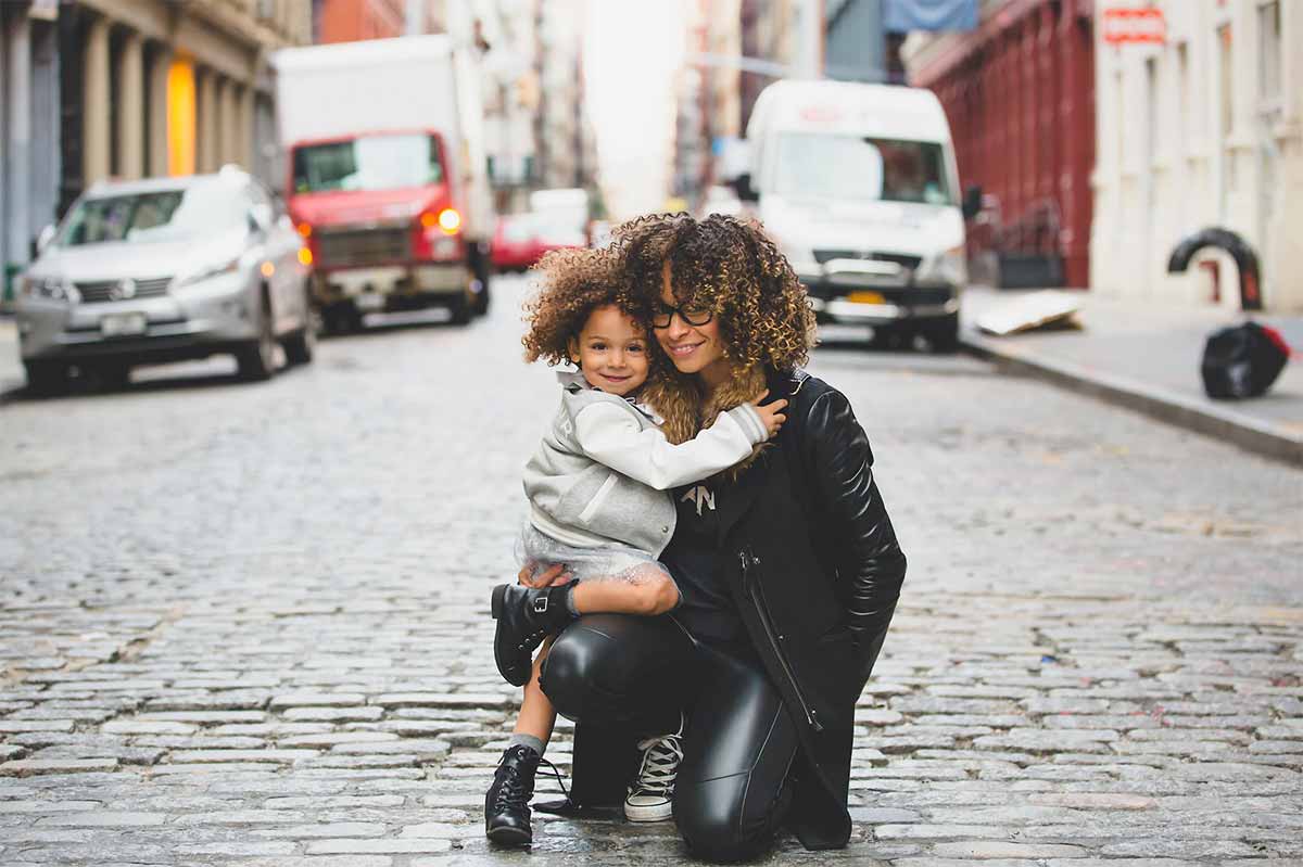 Photo d'une femme et sa fille dans ses bras dans la rue