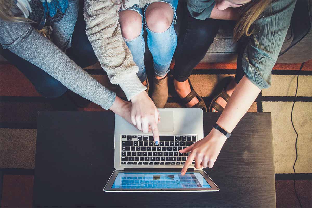 Photo trois personnes pointant un macbook